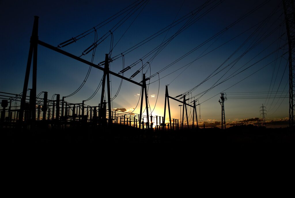 High-voltage electrical substation silhouetted at sunset, illustrating the power-grid bottleneck facing AI data centres.