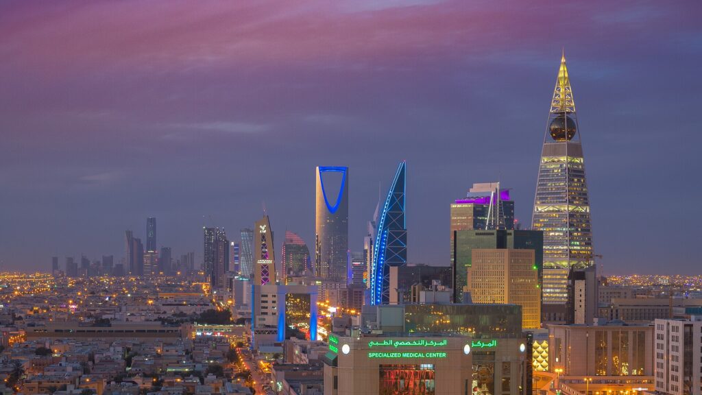 Riyadh skyline illuminated at night, with towers and city lights; illustrative image for the Future Investment Initiative conference postponement.